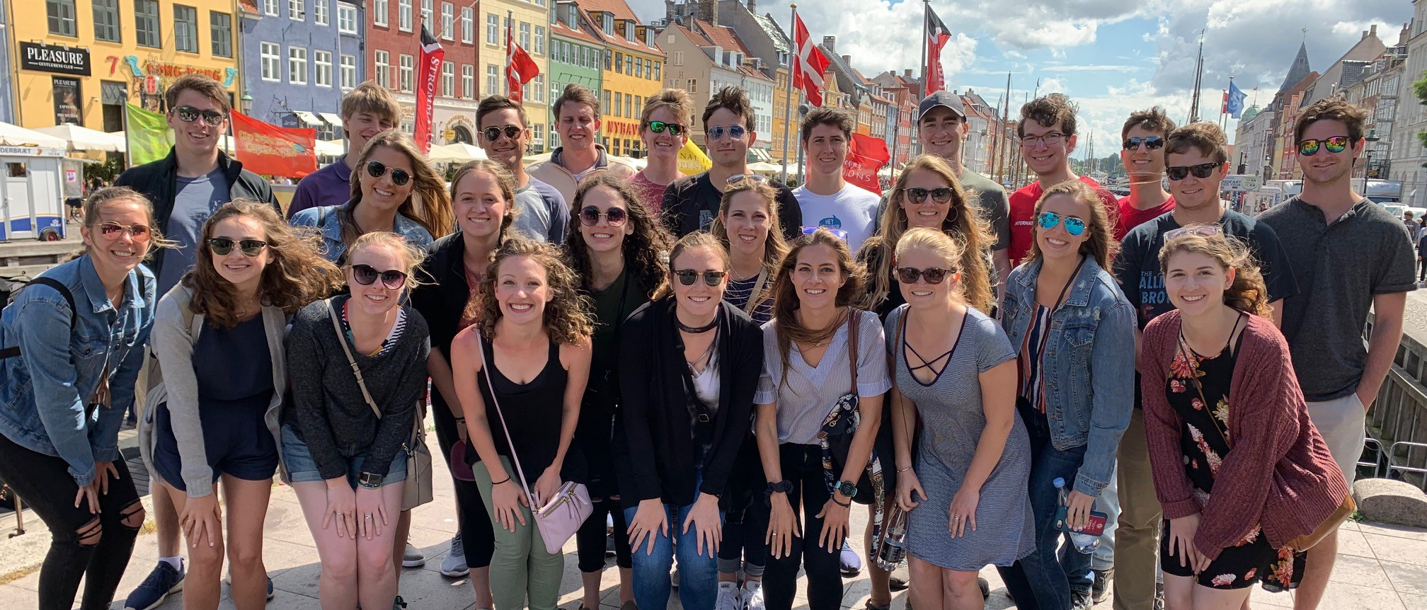 Group picture in the street with colorful houses and flags flying in background